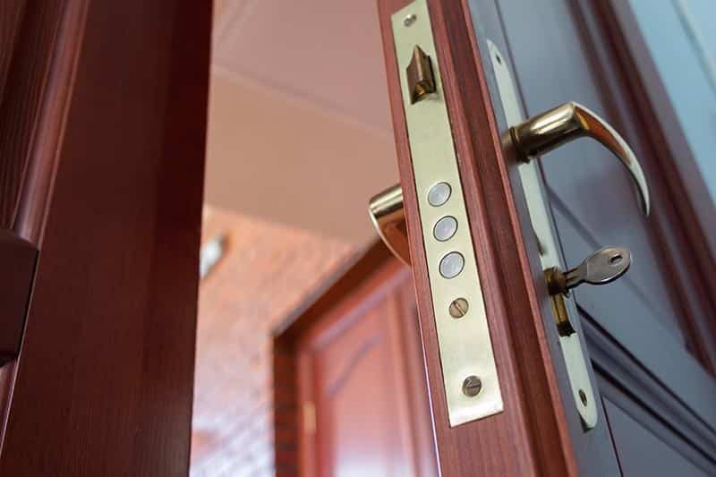 An open wooden door with a shiny door handle.