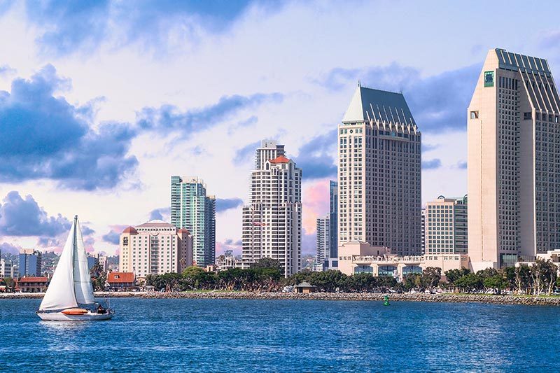 A sailboat on the water with a view of Downtown San Diego in California.