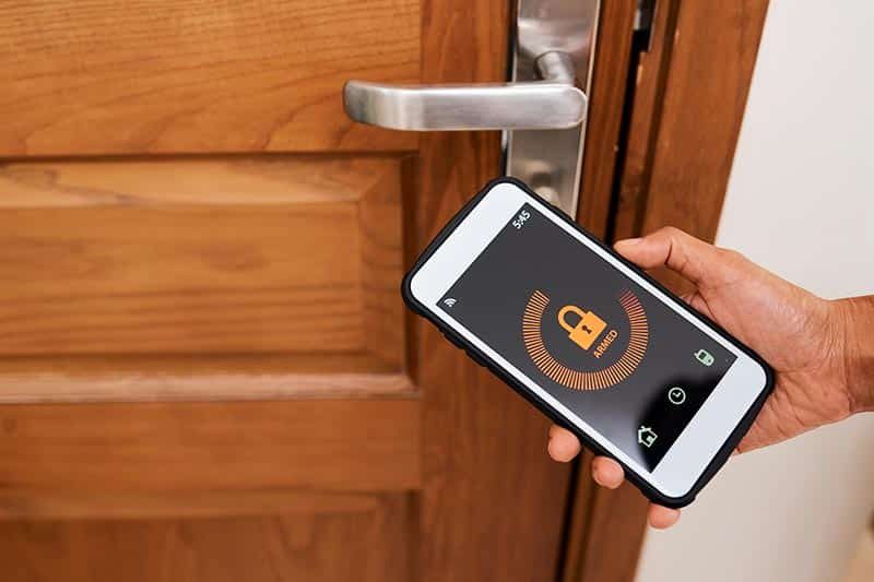 smart-security-system-locked-house-doors Activating a home security system from a smart phone.
