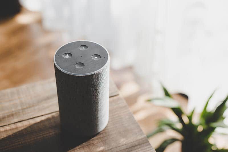 A smart speaker on a wooden table in a home in a 55+ community.