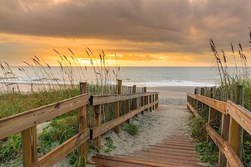 View along a boardwalk of a sunrise over a sand dune in Myrtle Beach, South Carolina.