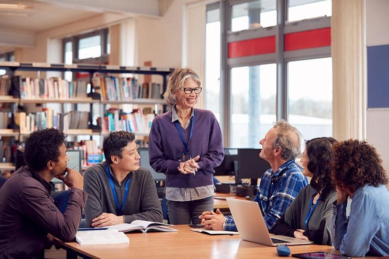 teacher-with-group-of-mature-adult-students-college-library