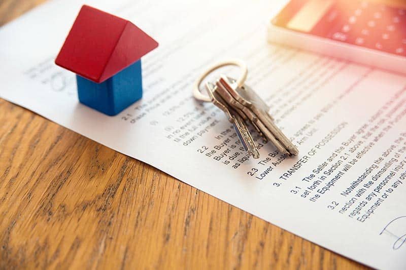 A miniature house and keys on a mortgage document.