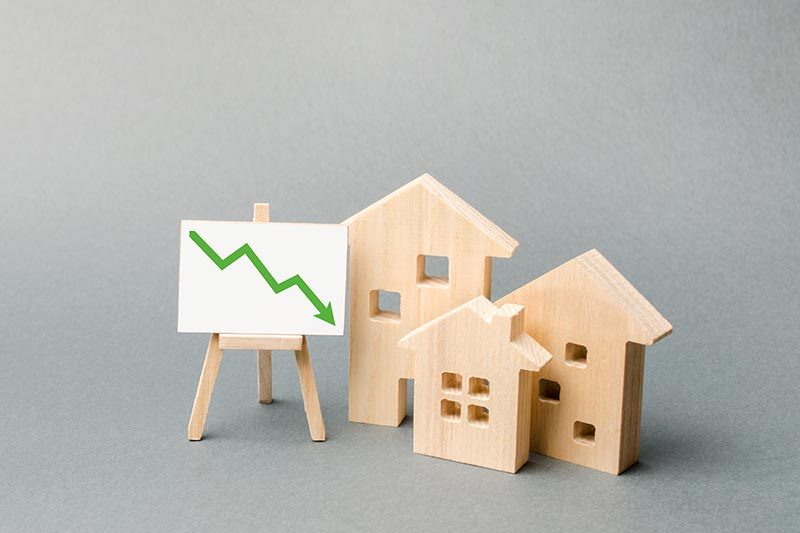Tiny wooden houses beside a tiny wooden easel with a green arrow pointed downward.